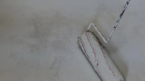 Hand holding a paint roller and applying fresh white paint on a concrete wall. Video stock 287645520