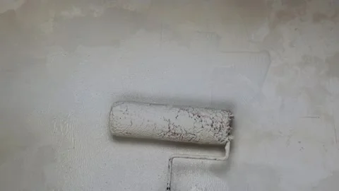 Hand holding a paint roller and applying fresh white paint on a concrete wall. Video stock 287647161