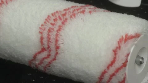 A Hand Holding a Paint Roller with Distinct Red Stripes Designed for Painting Видео 281328246