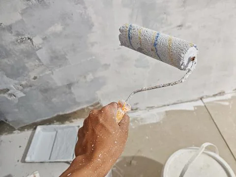 Hand Holding Paint Roller During Interior Wall Painting and Home Renovation Фото