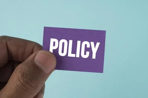Hand holding a paper document labeled POLICY, representing rules, guideline.. Stock Photos