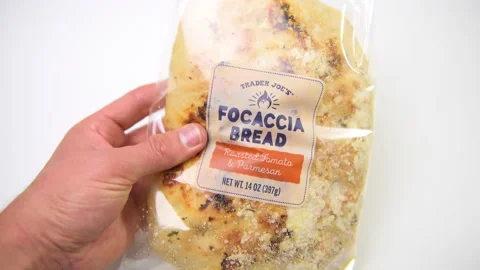 Hand holding parmesan cheese roasted tomatoes focaccia bread of Trader Joe's Stock Footage
