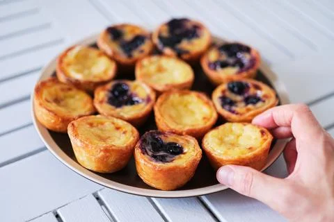 Hand holding Pasteis de Belem, Portuguese pastel de Nata Custard Tarts. Stock-Fotos