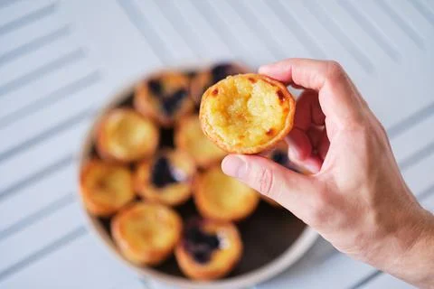 Hand holding Pasteis de Belem, Portuguese pastel de Nata Custard Tarts. Stock-Fotos