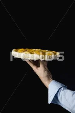 A hand holding a peach tart, studio shot Stock Photos
