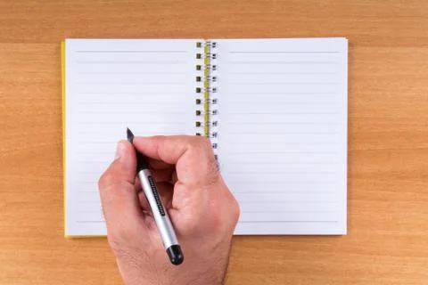 Hand holding pen on notebook Stock Photos