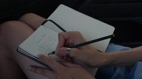 Hand holding a pen over a lined notepad, creating a yearly goals list. Stock Footage 323128997