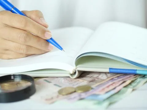 Hand holding pen to take notes and count money on the desk. Financial busin.. Stock Photos
