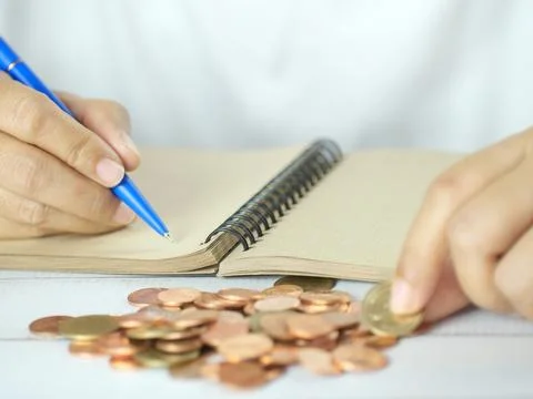 Hand holding pen to take notes and count money on the desk. Financial busin.. Stock Photos