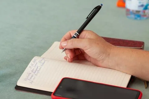 Hand holding pen while writing in notebook Stock Photos