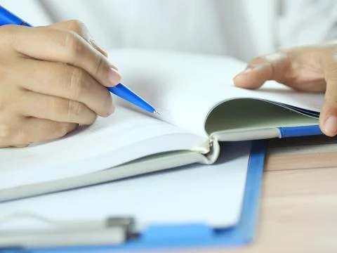 Hand holding pen writing on note paper. Finance business concept. Copy space. Stock Photos