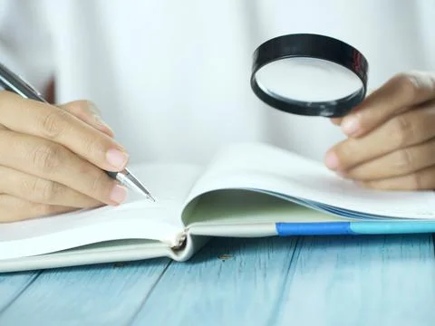 Hand holding pen writing on note paper. Finance business concept. Copy space. Stock Photos