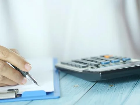 Hand holding pen writing on note paper. Finance business concept. Copy space. Stock Photos