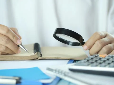 Hand holding pen writing on note paper. Finance business concept. Copy space. Stock Photos