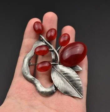 Hand holding pendant with red ruby and silver leaf on black background Stock Photos