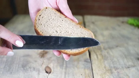 A hand holding a piece of bread on a cutting board Stock Footage 136426229