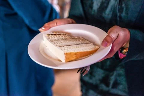Hand holding a piece of multi layer wedding cake on a plate Stock Photos