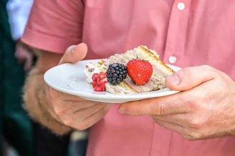 Hand holding a piece of multi layer wedding cake on a plate Stock Photos