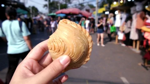 Hand holding a piece of Thai curry puff and take a bite Stock Footage 120619445