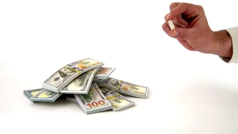Hand Holding Pill with Bunch of Dollars on White Background Stock Footage 76514583