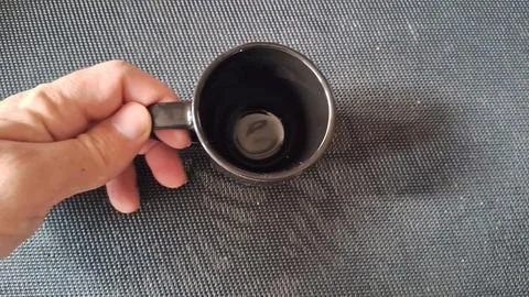 Hand holding a plain black ceramic coffee mug from above Stock Photos