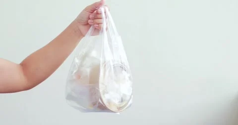 Hand holding plastic bag filled with food waste and used packaging, plastic.. Stock Footage 345647009