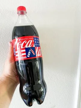 Hand holding a plastic bottle of Coca-Cola with a patriotic red, white, and.. Stockfoto's