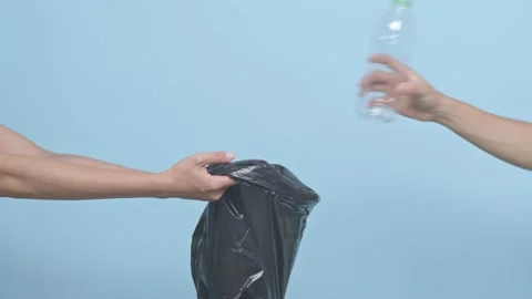 Hand holding plastic bottles to dispose in garbage bag ready to recycle on bl Stock Footage 149813385