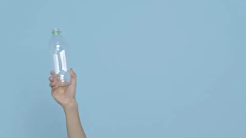 Hand holding plastic bottles ready to recycle on blue background. waste manag Stock Footage 149813431