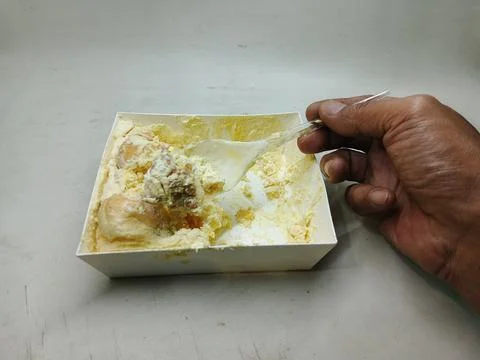 Hand holding a plastic spoon scooping traditional durian whipped cream dessert. 库存照片