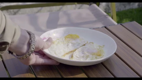 Hand Holding Plate with Two Fried Eggs on Wooden Table in Morning Sunlight – 4K  스톡 동영상 327055083