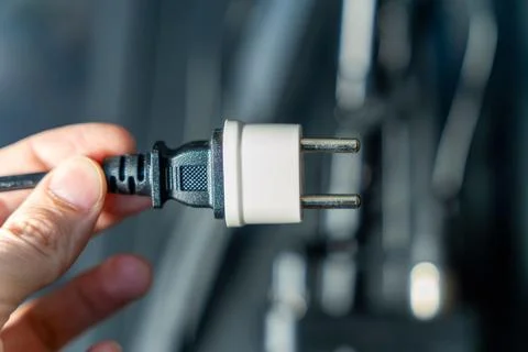 Hand holding a plug ready to connect to a socket in a power outlet Stock Photos