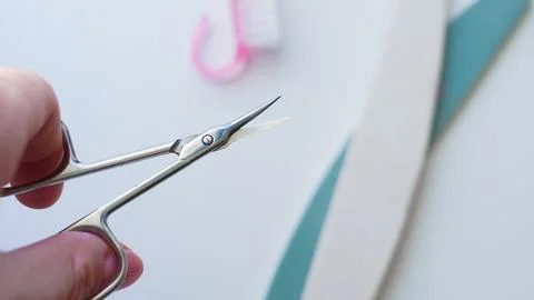 Hand holding precision scissors over crafting materials on white surface Stock Photos