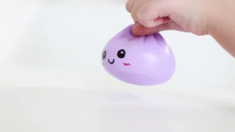 Hand holding purple dumpling squishy toy with a smiling face Stock Footage 334434235