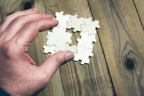 A hand is holding a puzzle piece that is missing Foto stock