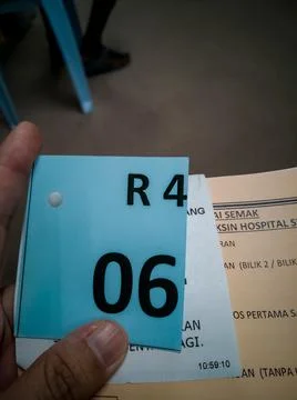 Hand holding a queue number vaccination ticket in Hospital Serdang. Stock Photos