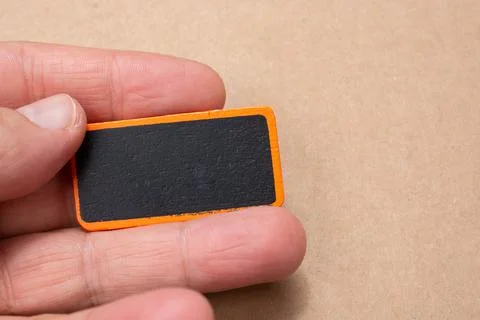 Hand holding a rectangular framed board in the light brown background 스톡 사진