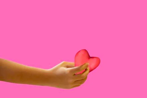 Hand holding a red candy shape heart on a pink background with clipping path Stock Photos