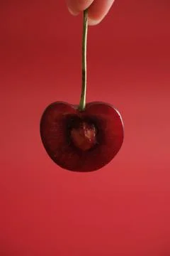 Hand holding red cherry on red background Stock Photos