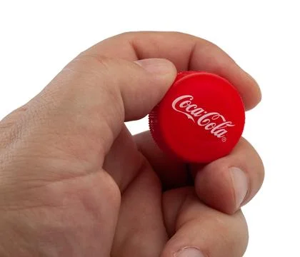 Hand holding red Coca-Cola bottle cap Stock Photos