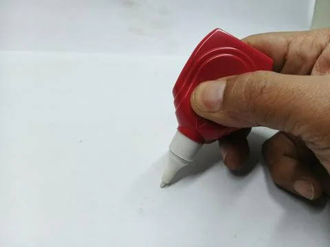Hand holding red correction fluid pen on white background 库存照片