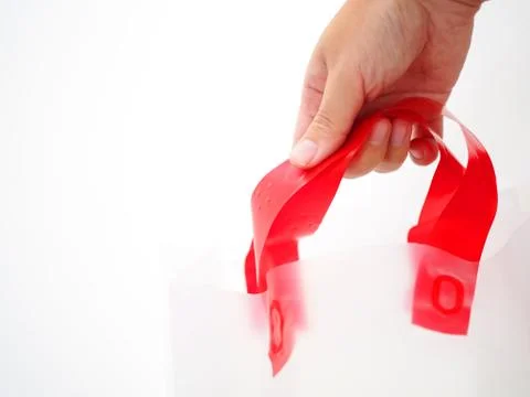Hand holding red handle plastic shopping bag, white background Foto stock