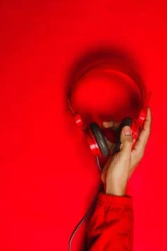 Hand holding Red headphones on red background. Music concept Stock Photos