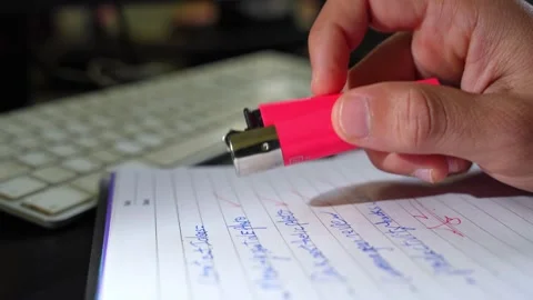 Hand Holding Red Lighter Over Notebook with Keyboard in Background Video stock 313119998