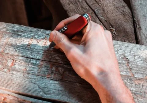 Hand holding a red multitool pocket knife carving a signature Stock Photos