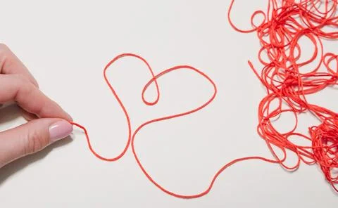 Hand holding red thread forming heart shape on white background Stock Photos