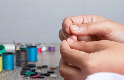 Hand holding the red threaded with stitching needles Foto stock