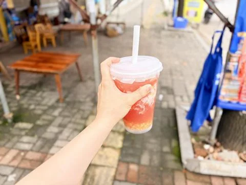 Hand Holding a Refreshing Fruit Bubble Tea on a Street Background Stock Photos