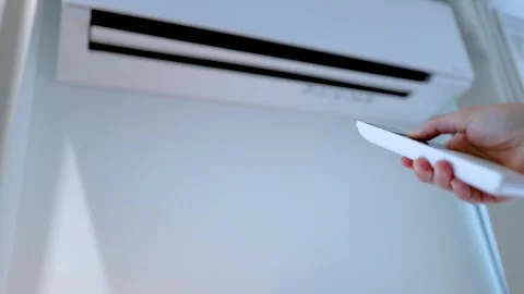 Hand Holding Remote Control to Adjust Wall Mounted Air Conditioner Temperature Stock Footage 333289074