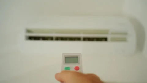 Hand holding a remote control, adjusting the temperature on a modern air Stock Footage 343270189